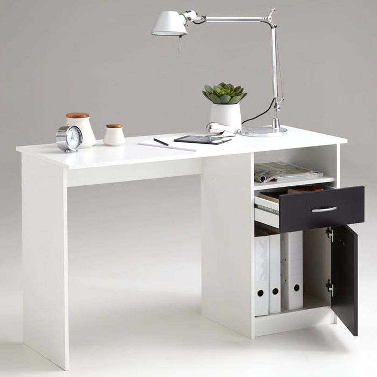 Ein weißer Schreibtisch mit Lampe, Uhr, Pflanze, Ordnern und offener Schublade.