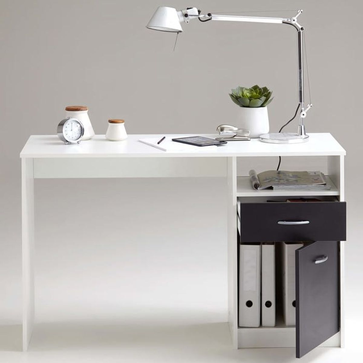 Ein weißer Schreibtisch mit Lampe, Uhr, Topfpflanze und Büromaterial.