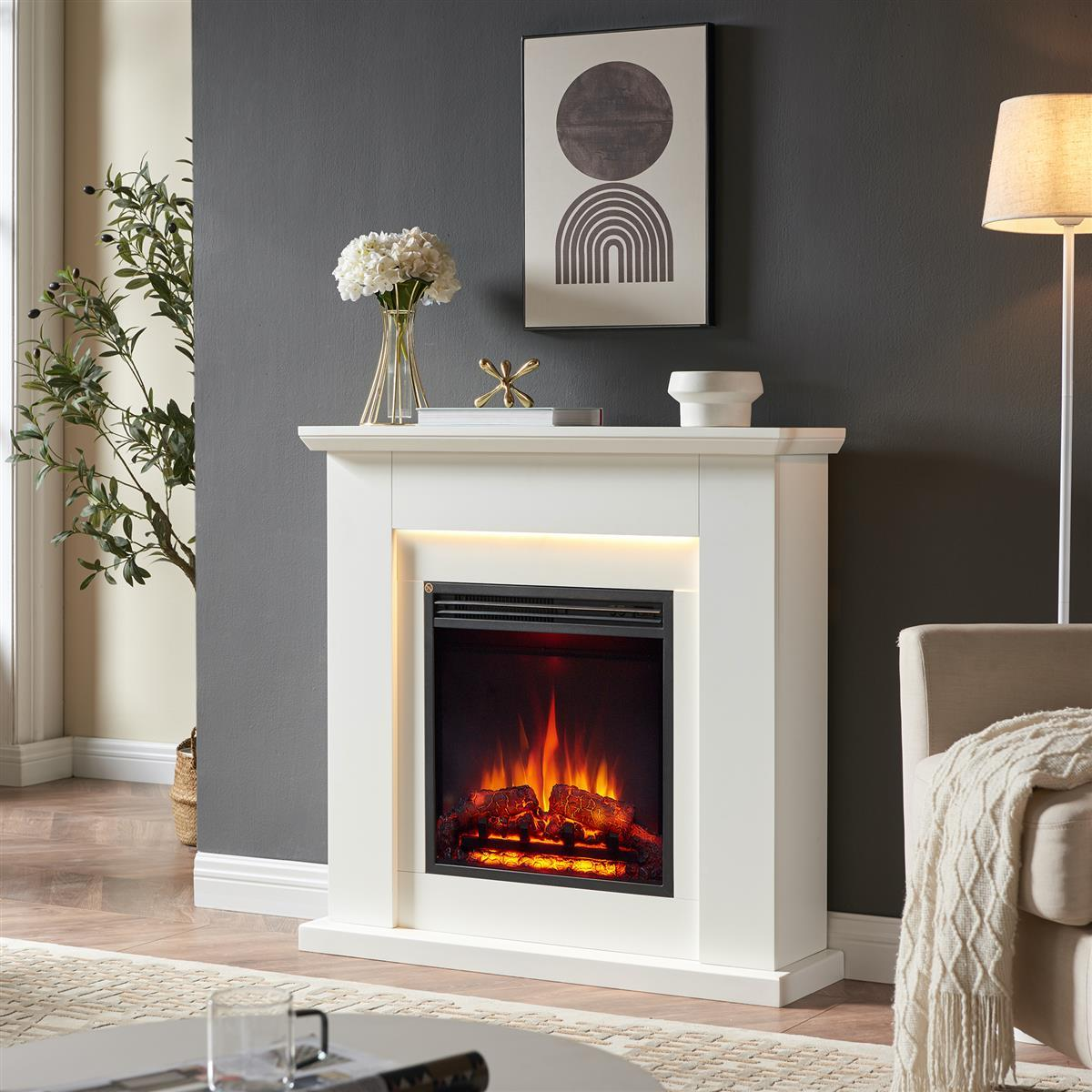 Ein weißer Kaminsims mit einem brennenden Kamin und Dekorationen.
