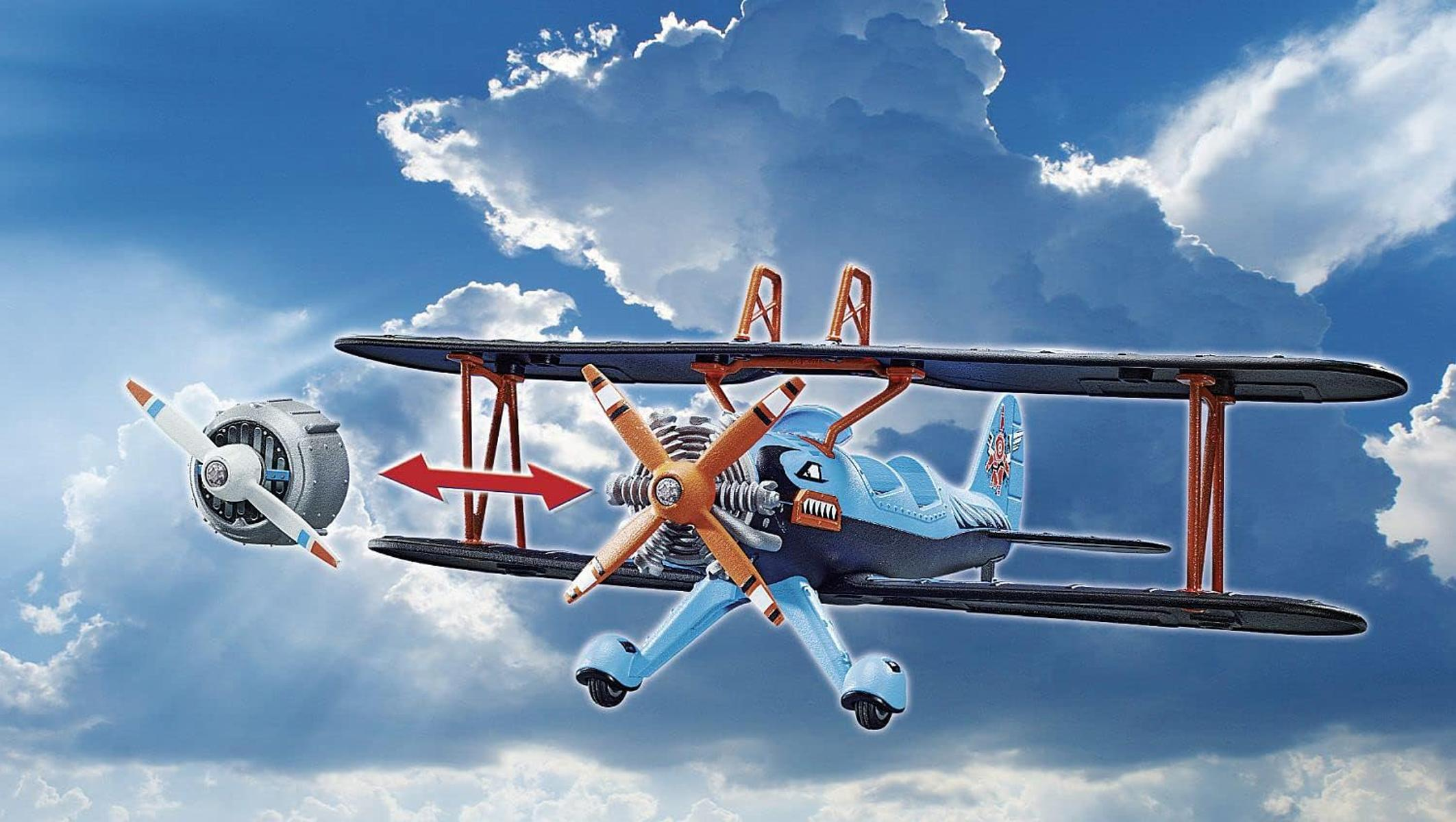 Un biplano azul con hélice naranja vuela en un cielo azul nublado.