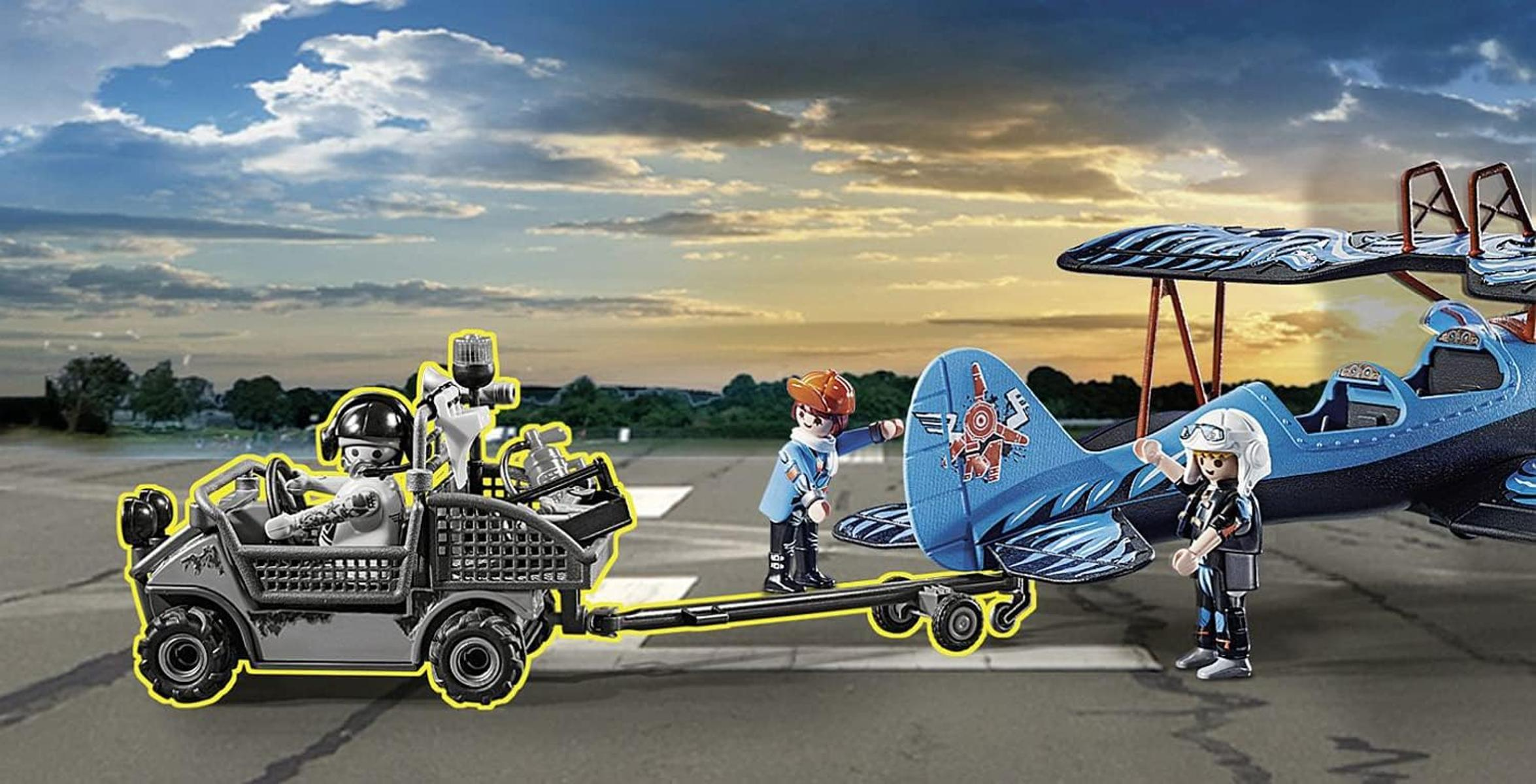 Figuras de juguete en un aeródromo con un avión azul y un vehículo.