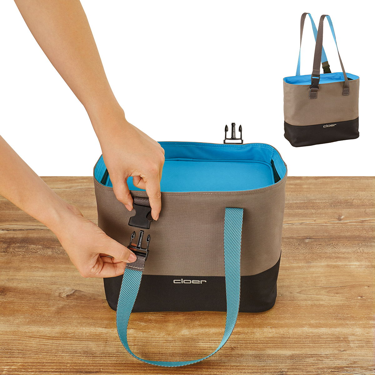 Hände schließen eine braune und schwarze Tasche mit blauem Innenfutter und Trägern.