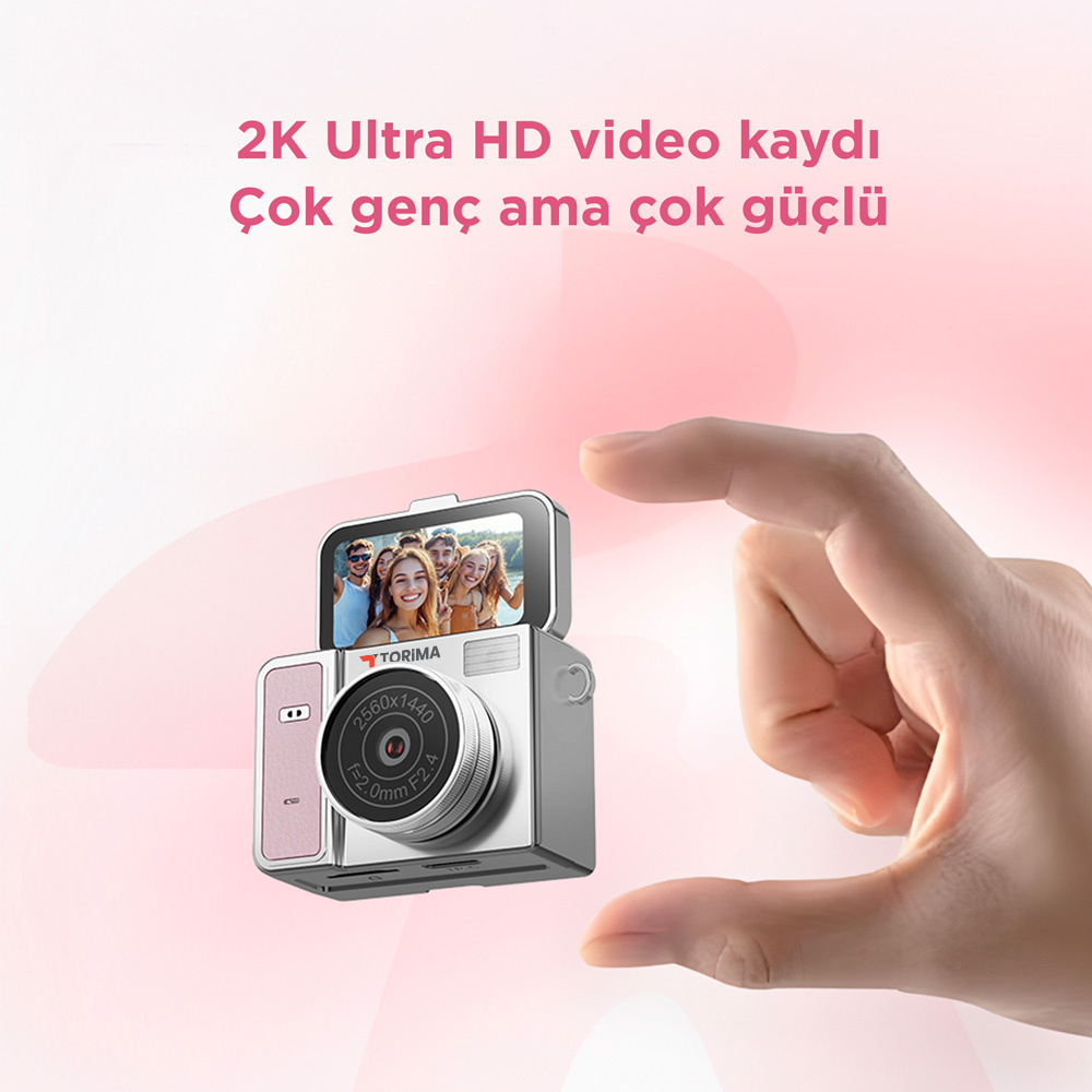 Pembe vurgulu küçük gümüş kamera bir el tarafından tutuluyor. Kamera selfie gösteriyor.