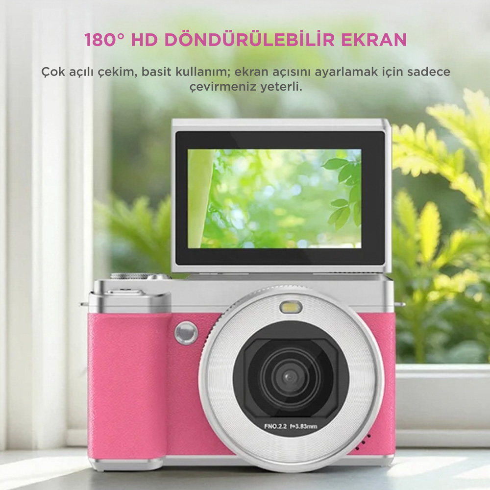 Pembe dijital fotoğraf makinesi, çevrilebilir ekranlı, masada duruyor.