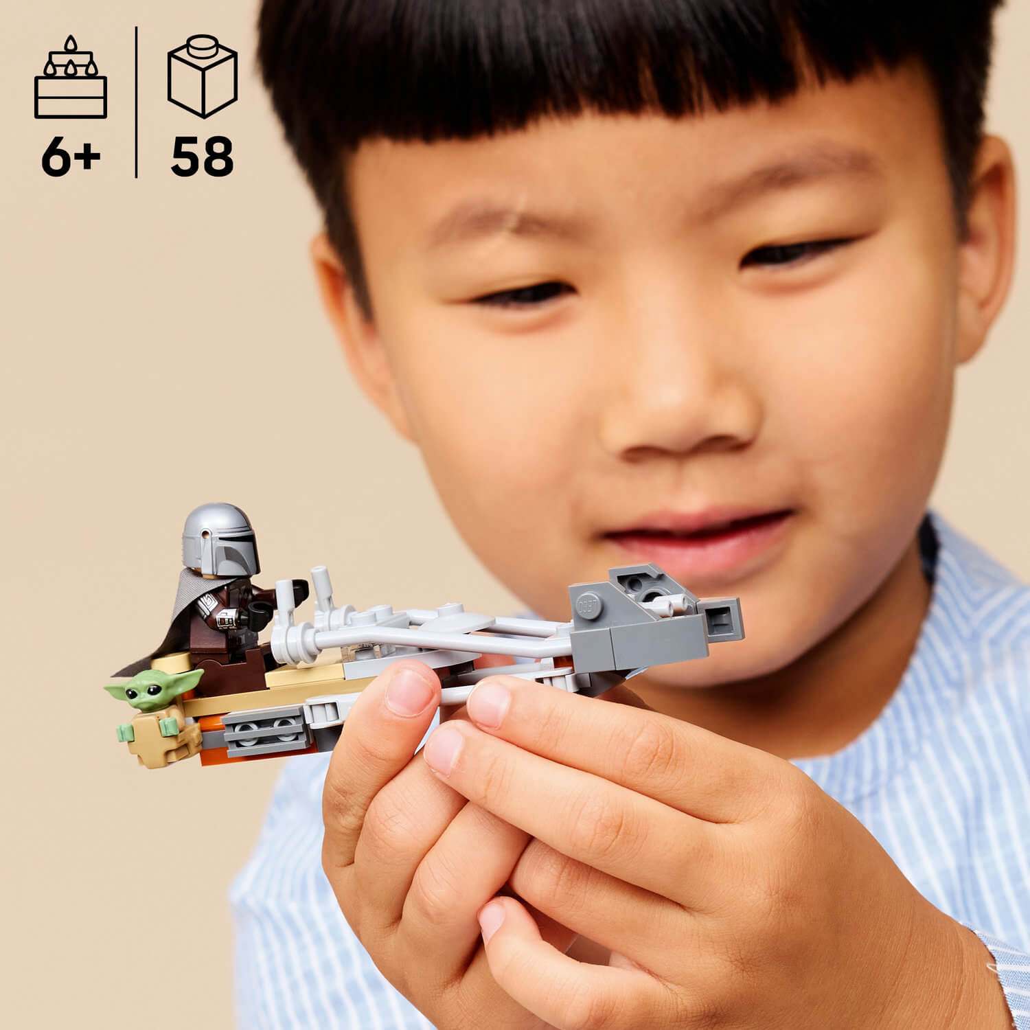 Çocuk, mandalorian ve Grogu'nun küçük bir Lego figürünü gri bir araç üzerinde tutuyor.