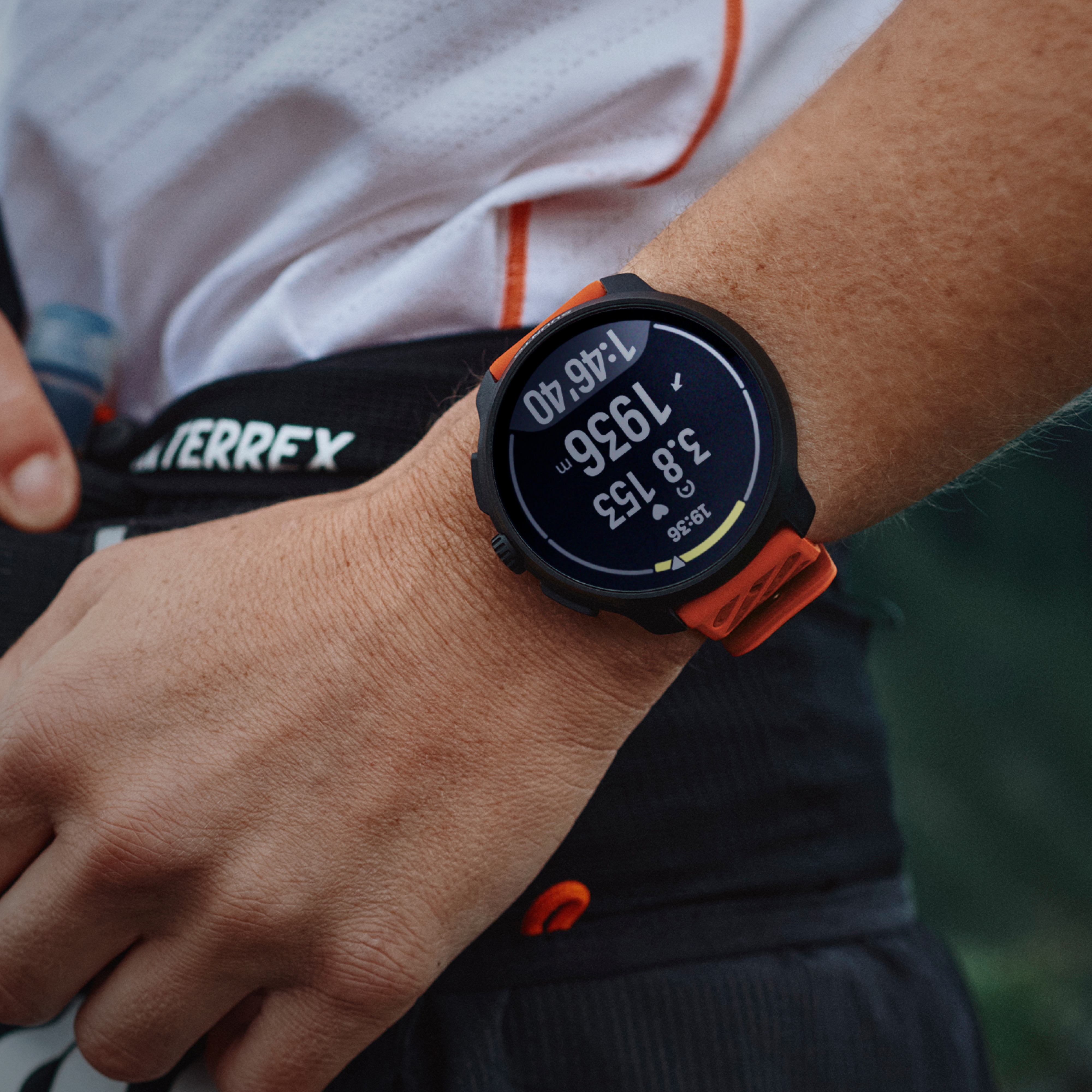Orologio sportivo con cinturino arancione al polso, mostra distanza e tempo.