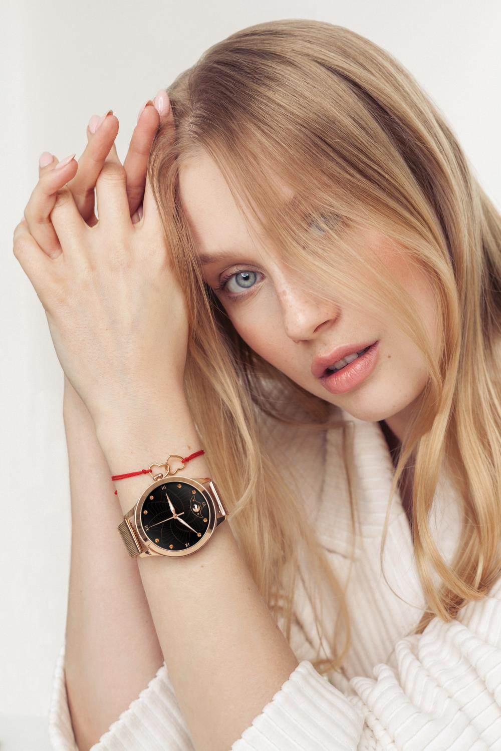 Eine Frau mit blauen Augen und blonden Haaren trägt eine Uhr am linken Handgelenk.