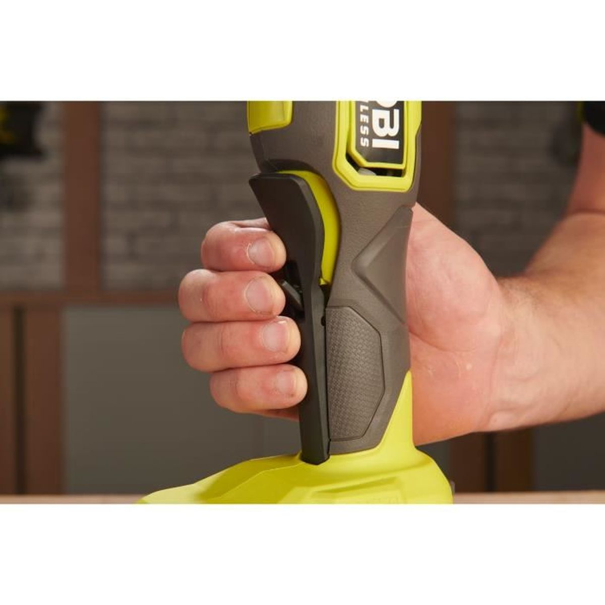 Mano tiene manico attrezzo cordless giallo e grigio con grilletto nero.