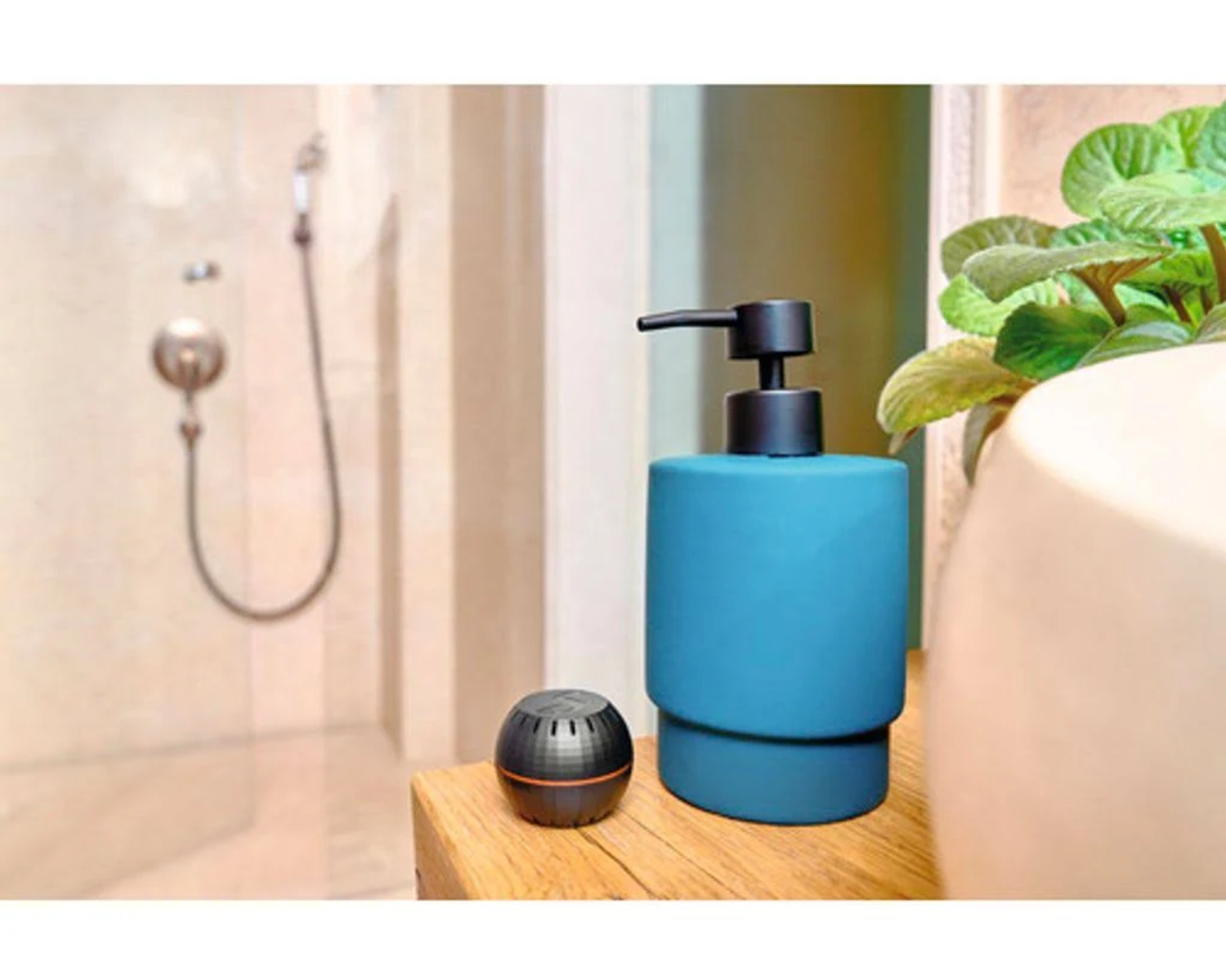 Dispenser sapone blu e piccolo contenitore nero su mensola di legno, doccia sullo sfondo.