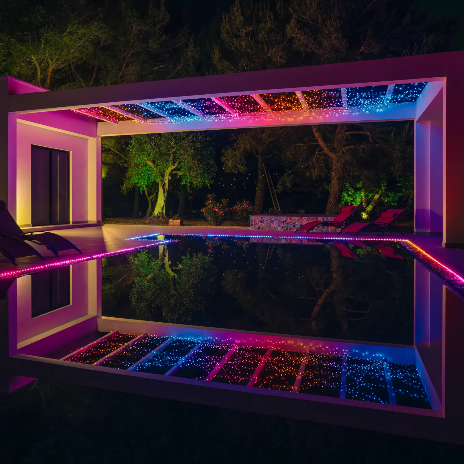 Nowoczesne patio z basenem nocą, oświetlone kolorowymi LEDami.