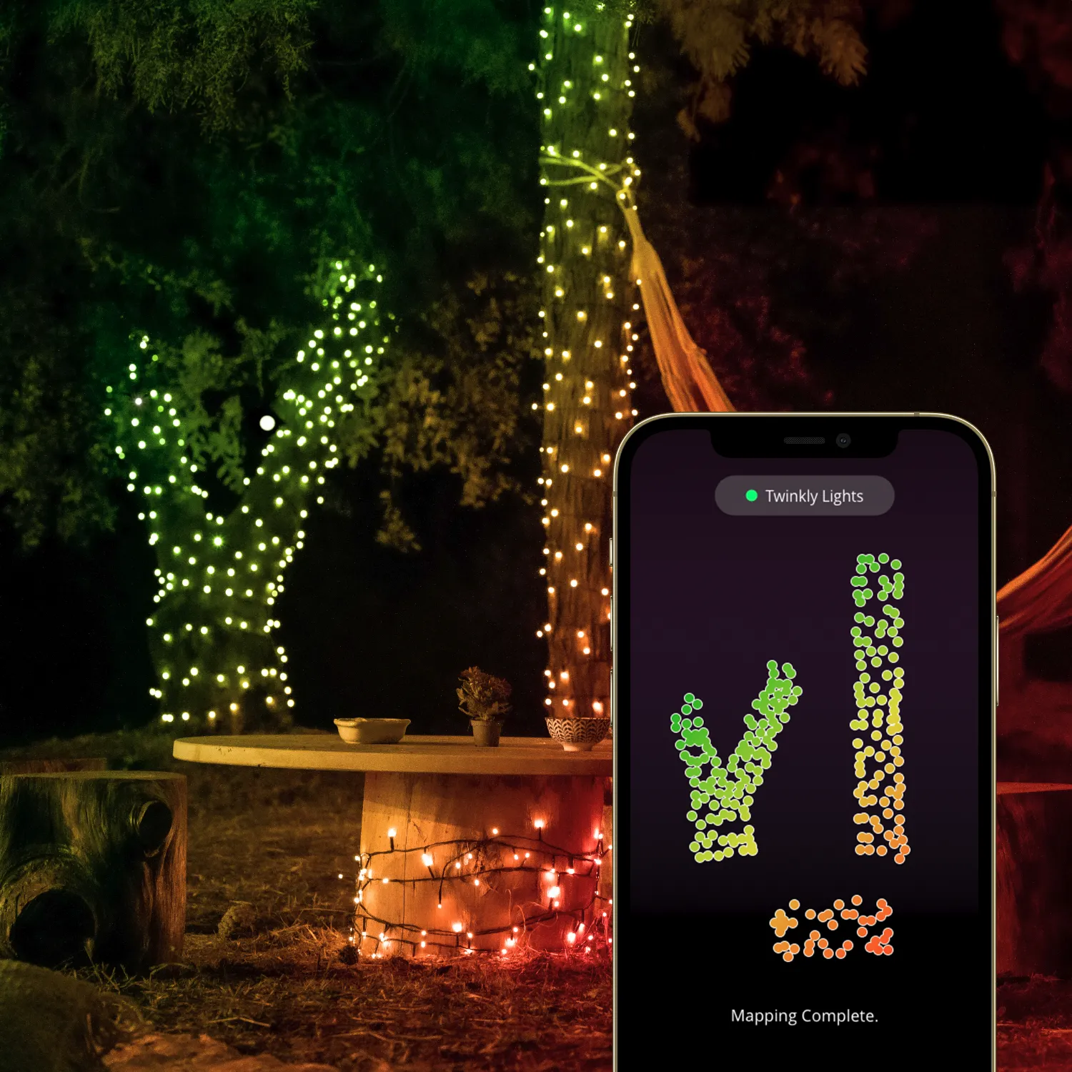 Drzewa i stół ozdobione kolorowymi światłami LED. Telefon pokazuje mapowanie świateł.