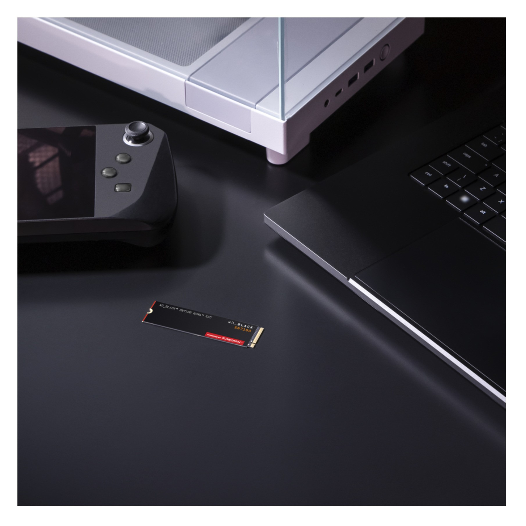 Urządzenie ręczne, laptop, dysk SSD i inne urządzenie na czarnej powierzchni.