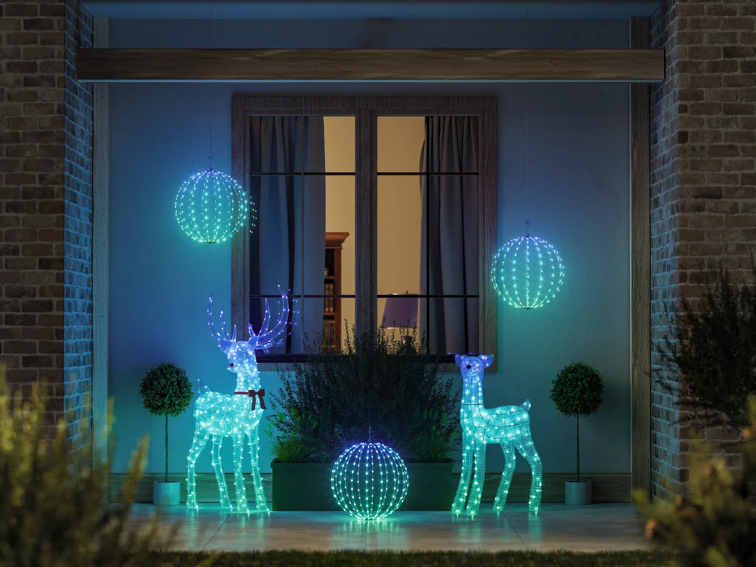 Podświetlane dekoracje reniferów i kul na werandzie nocą.
