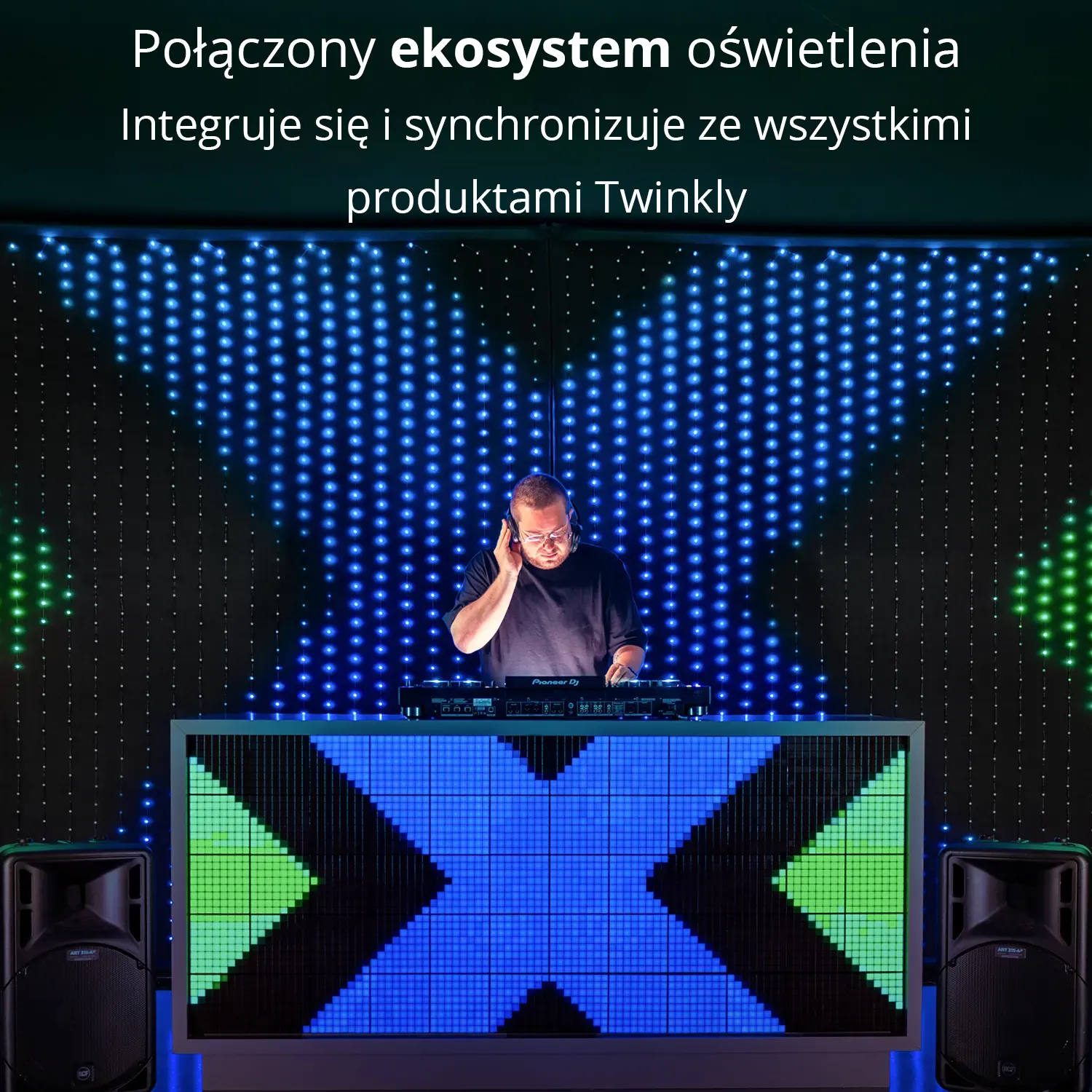 DJ w słuchawkach stoi za konsolą DJ-ską z efektami świetlnymi i głośnikami LED.