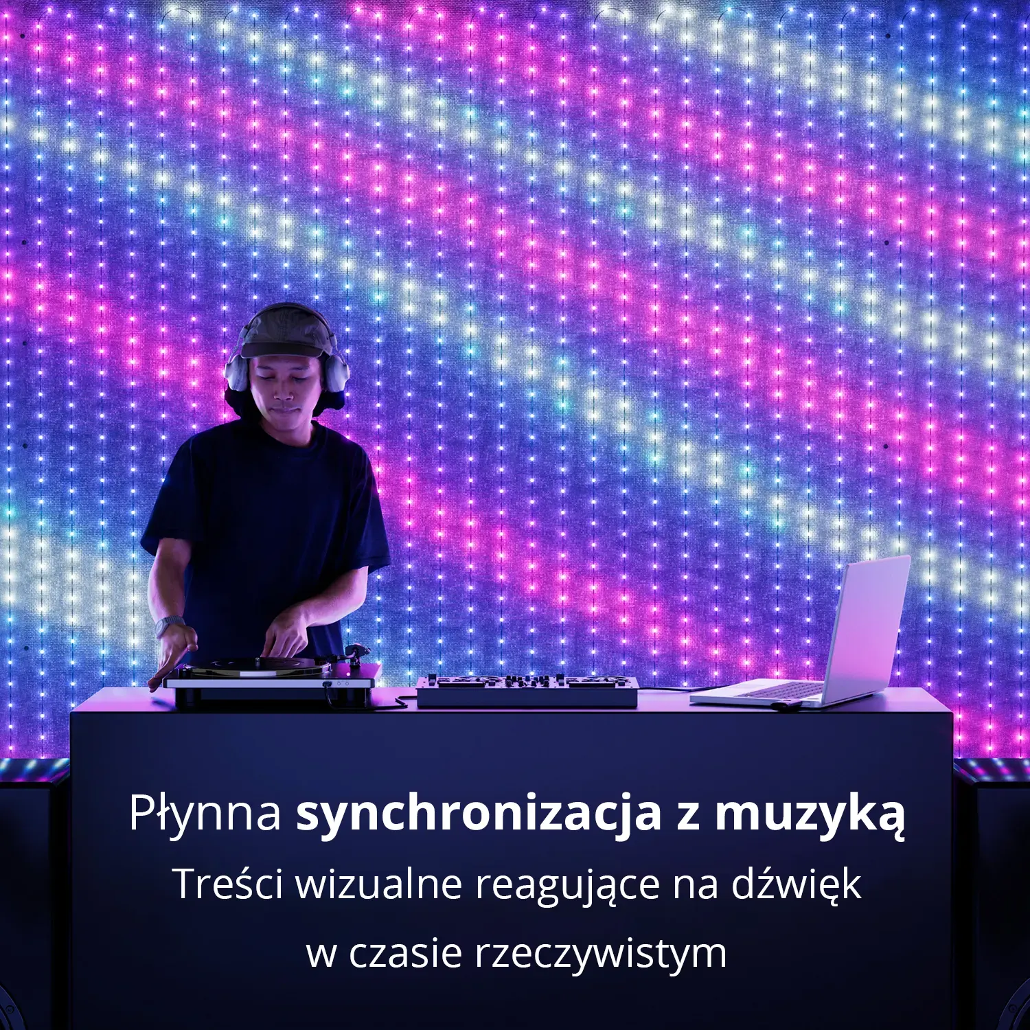 DJ w słuchawkach występuje przed żywą ścianą niebieskich, różowych i białych świateł.