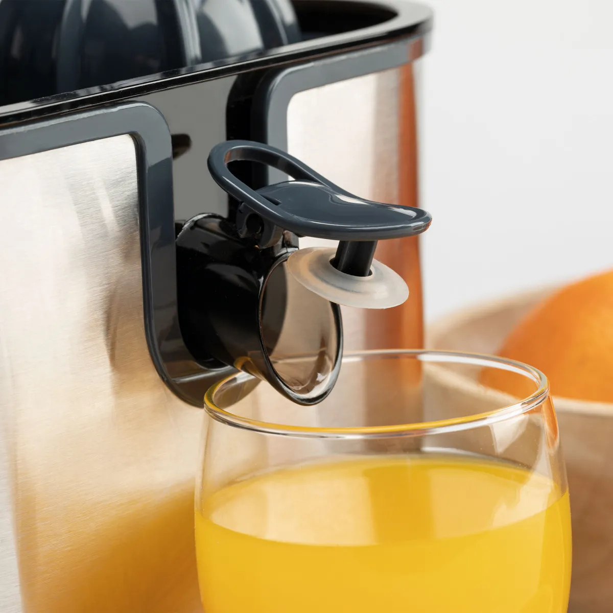 Un bicchiere di succo d'arancia davanti a uno spremiagrumi. Parte di un'arancia visibile.