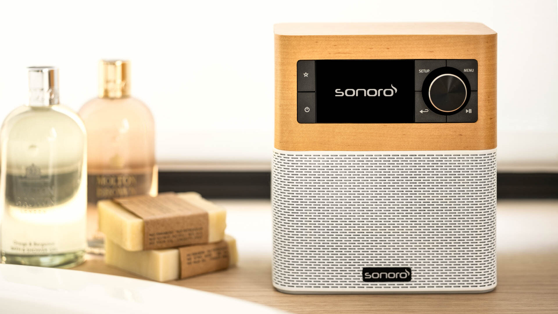 Drewniane radio z kratką głośnika obok mydeł i balsamów.