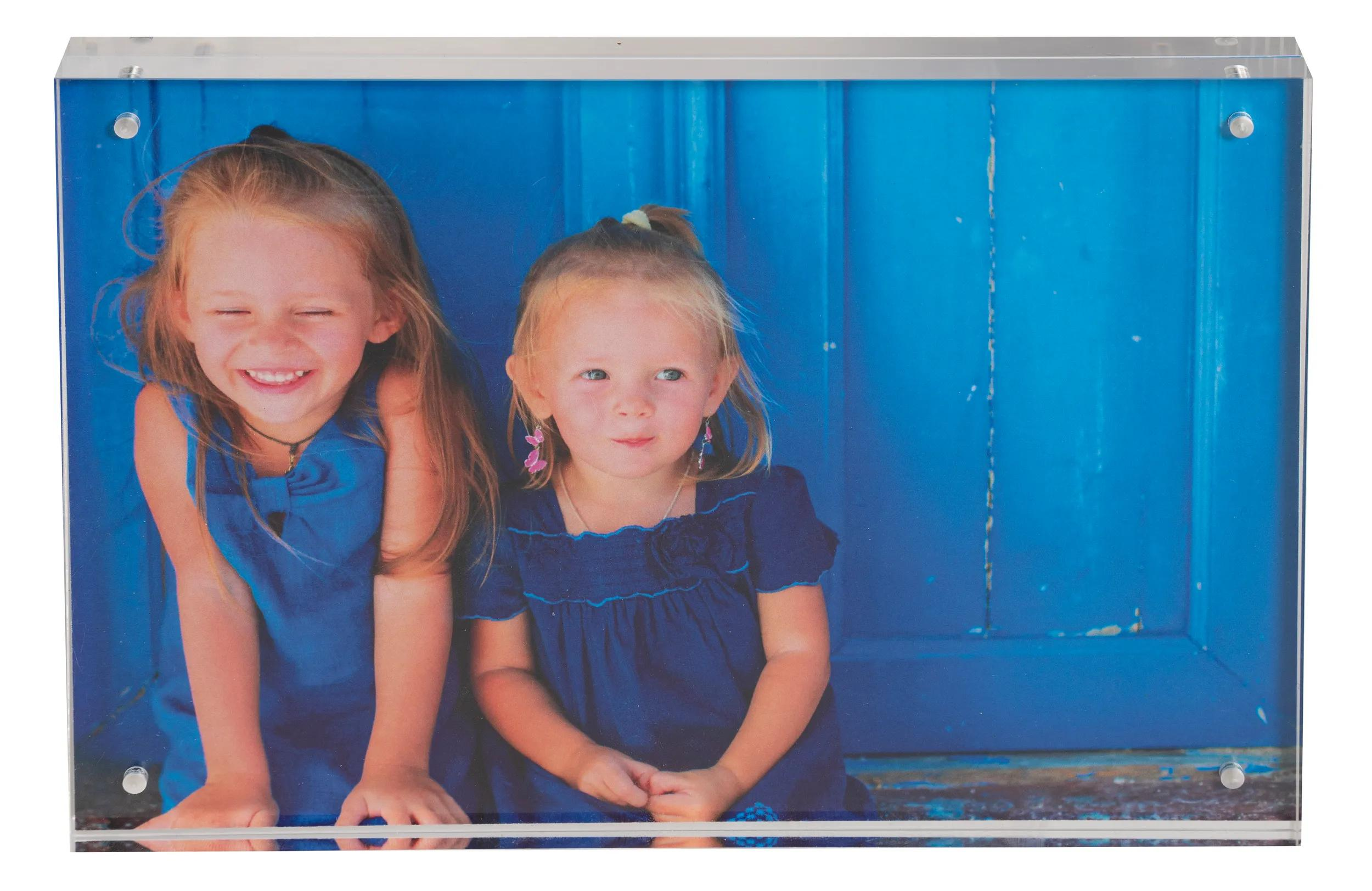 Dos niñas con vestidos azules sentadas frente a una puerta de madera azul.