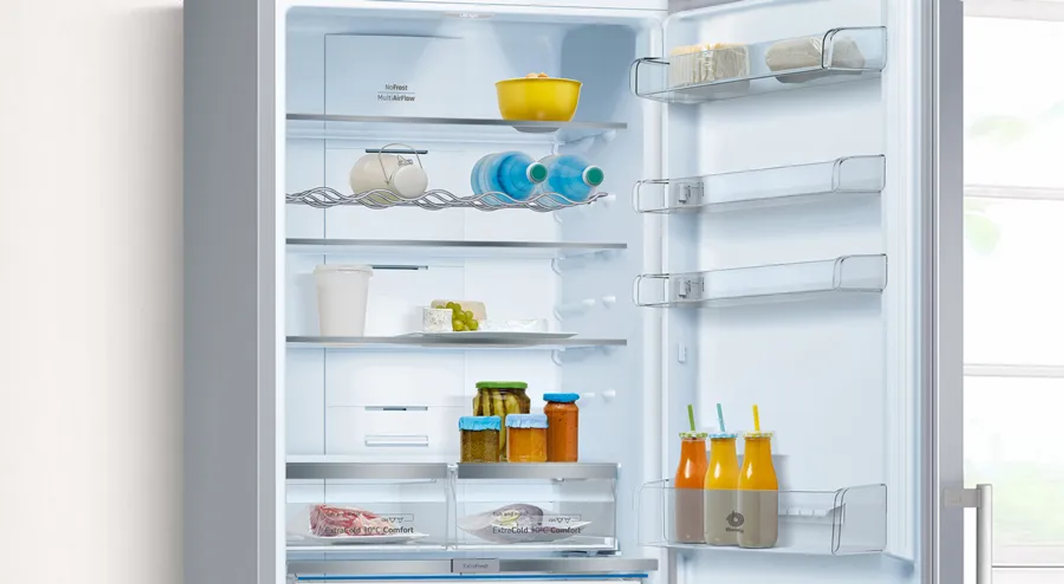 Refrigerador abierto con comida: tazón amarillo, botellas, frascos, bebidas, carne, uvas.