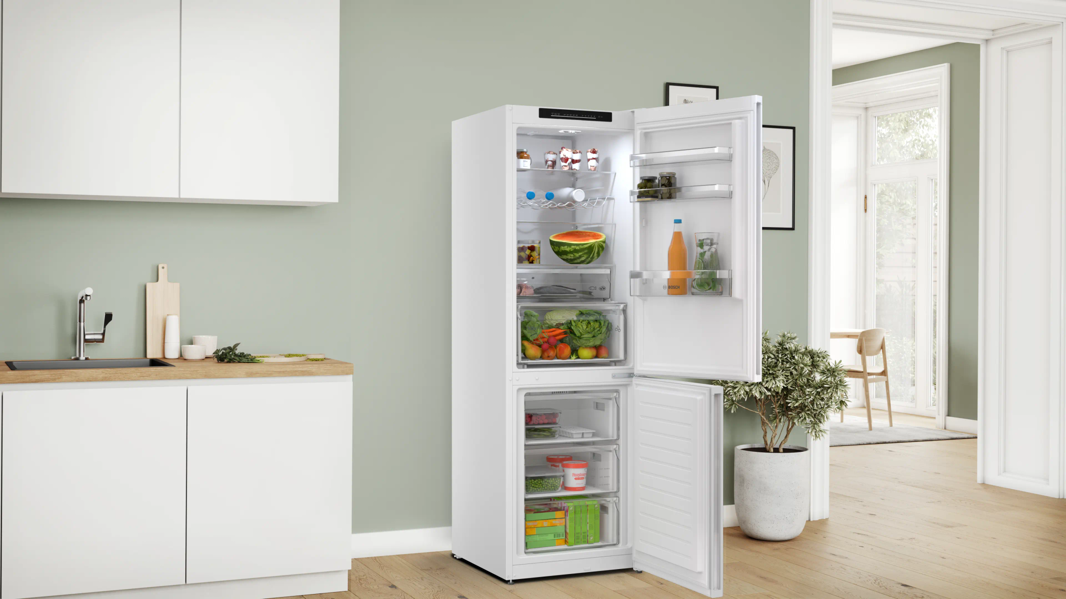 Refrigerador blanco abierto con comida, junto a una encimera de cocina.