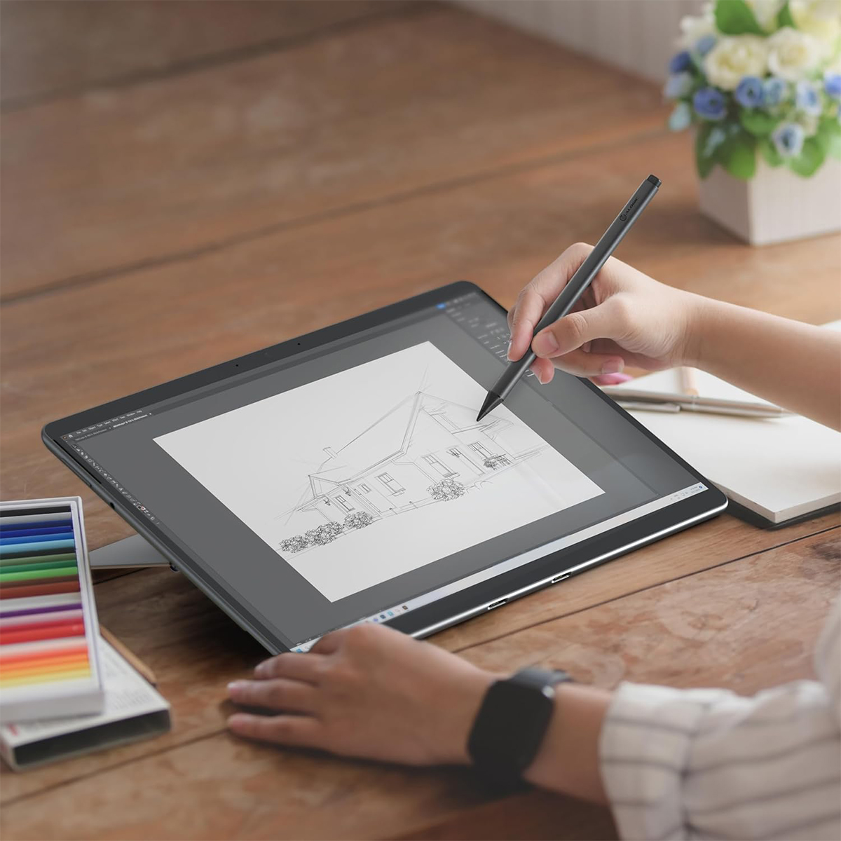 Osoba rysuje dom na tablecie rysikiem.