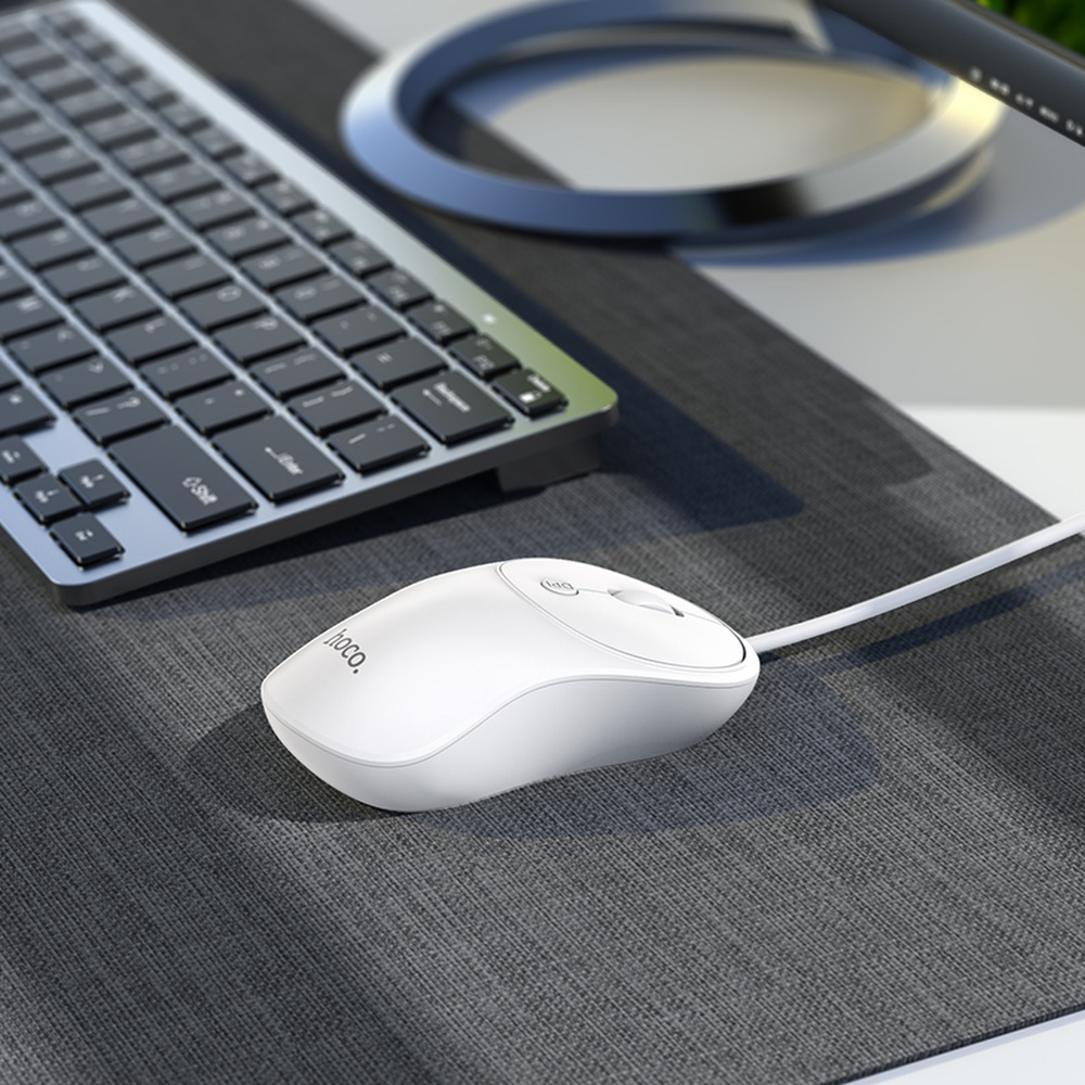 Un ratón y teclado blancos descansan sobre un alfombrilla gris.