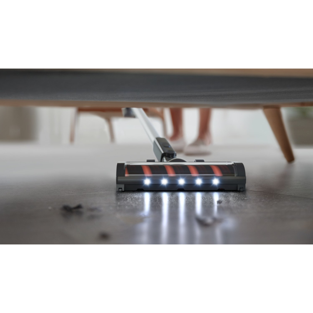 Szczotka odkurzacza ze światłami czyści podłogę pod sofą.