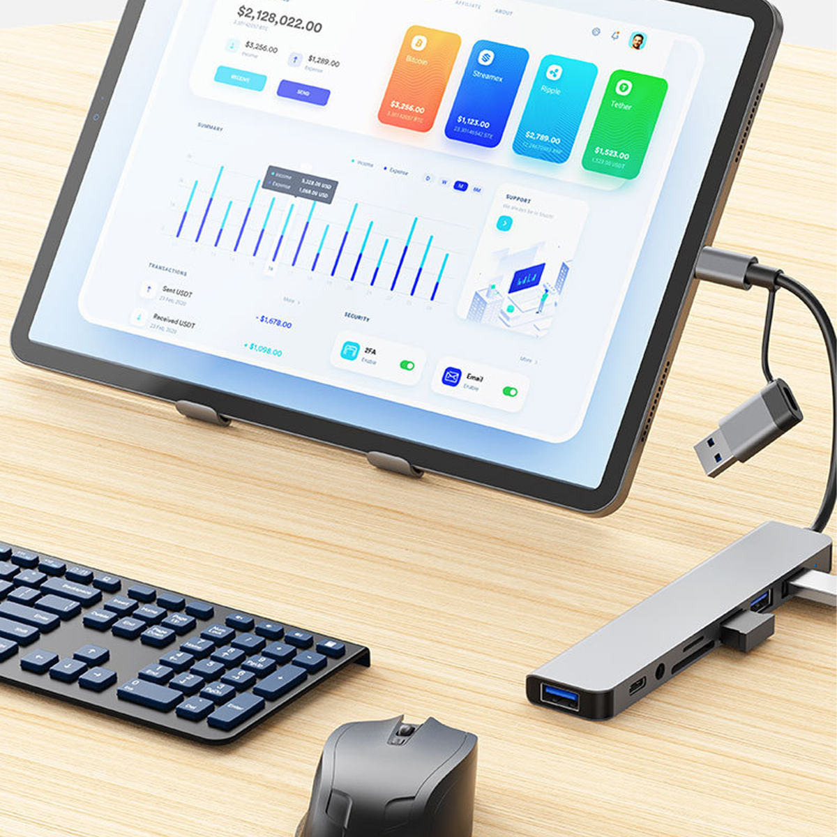 Tablet mit Finanzdiagrammen, Tastatur, Maus und USB-Hub auf einem Holztisch.