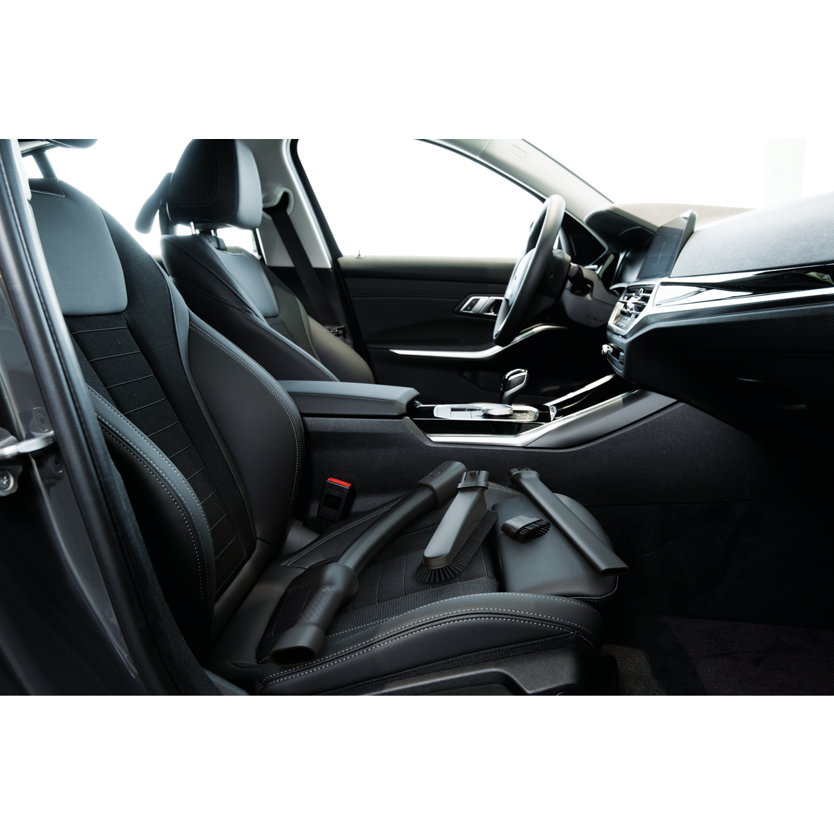 Interior de un coche con asientos de cuero negro y accesorios de aspiradora.