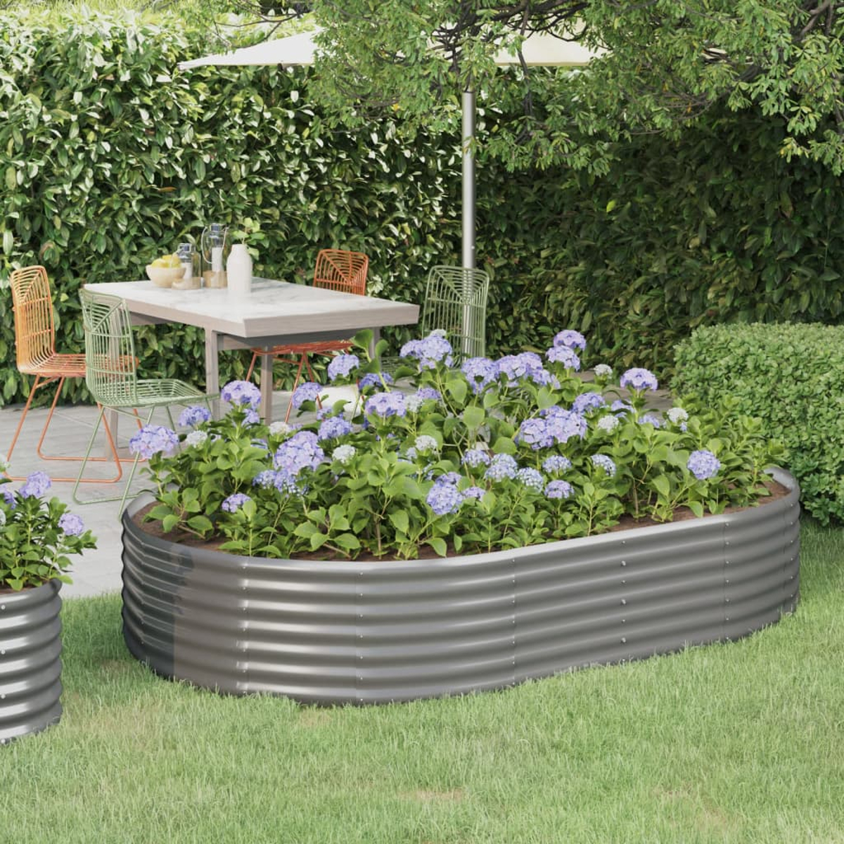 Ein Garten mit einem rechteckigen Hochbeet, gefüllt mit blauen Hortensien.