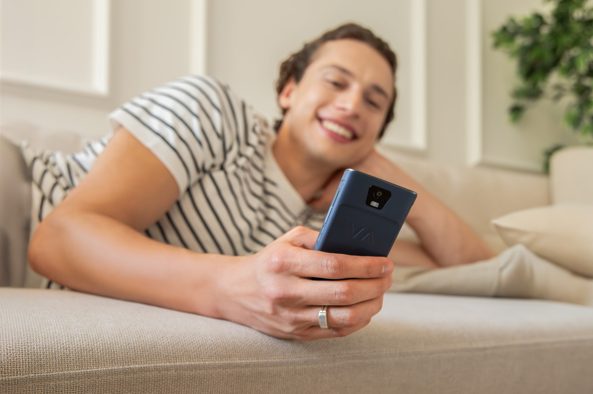 Ein Mann liegt auf einer Couch und hält ein Smartphone in der Hand.