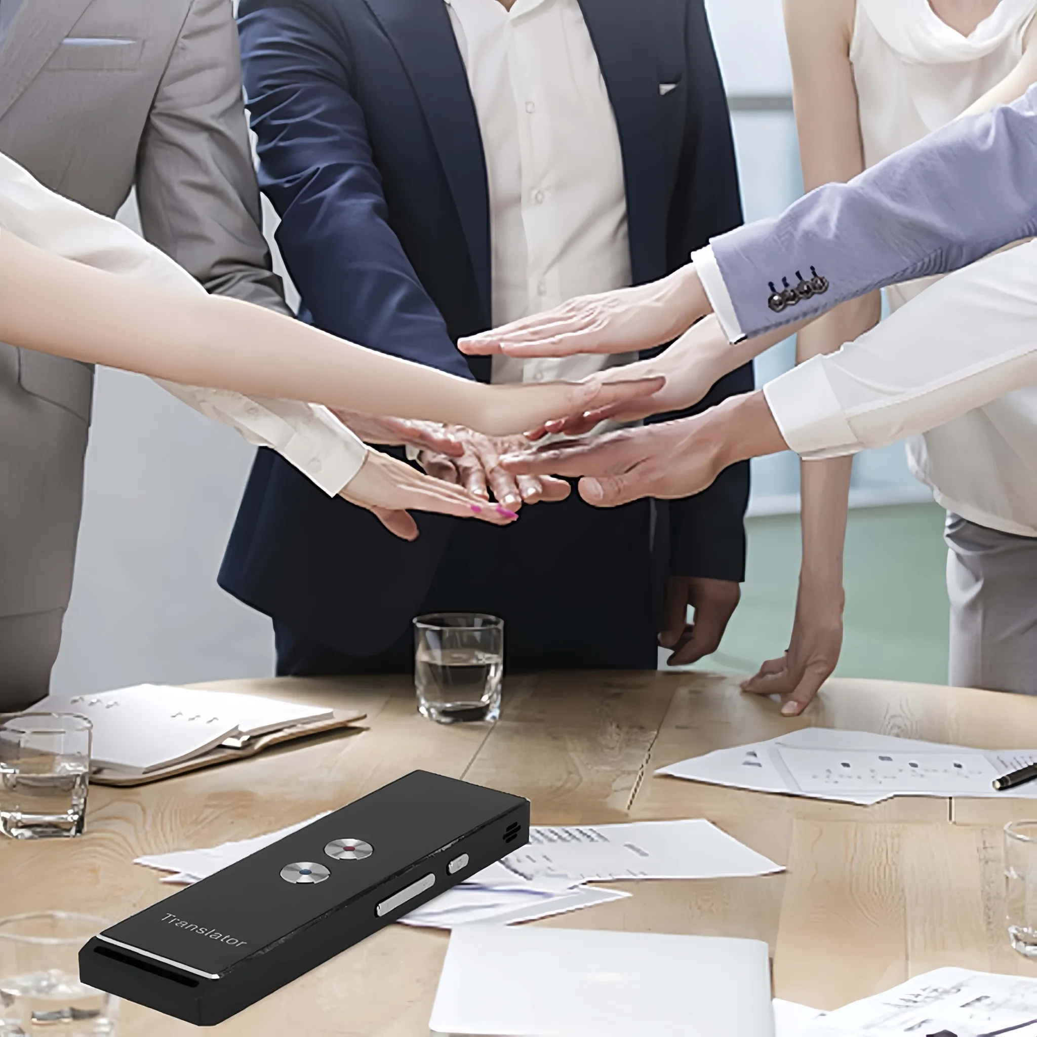 Geschäftsleute legen Hände für Teamwork auf einen Tisch mit Übersetzer.