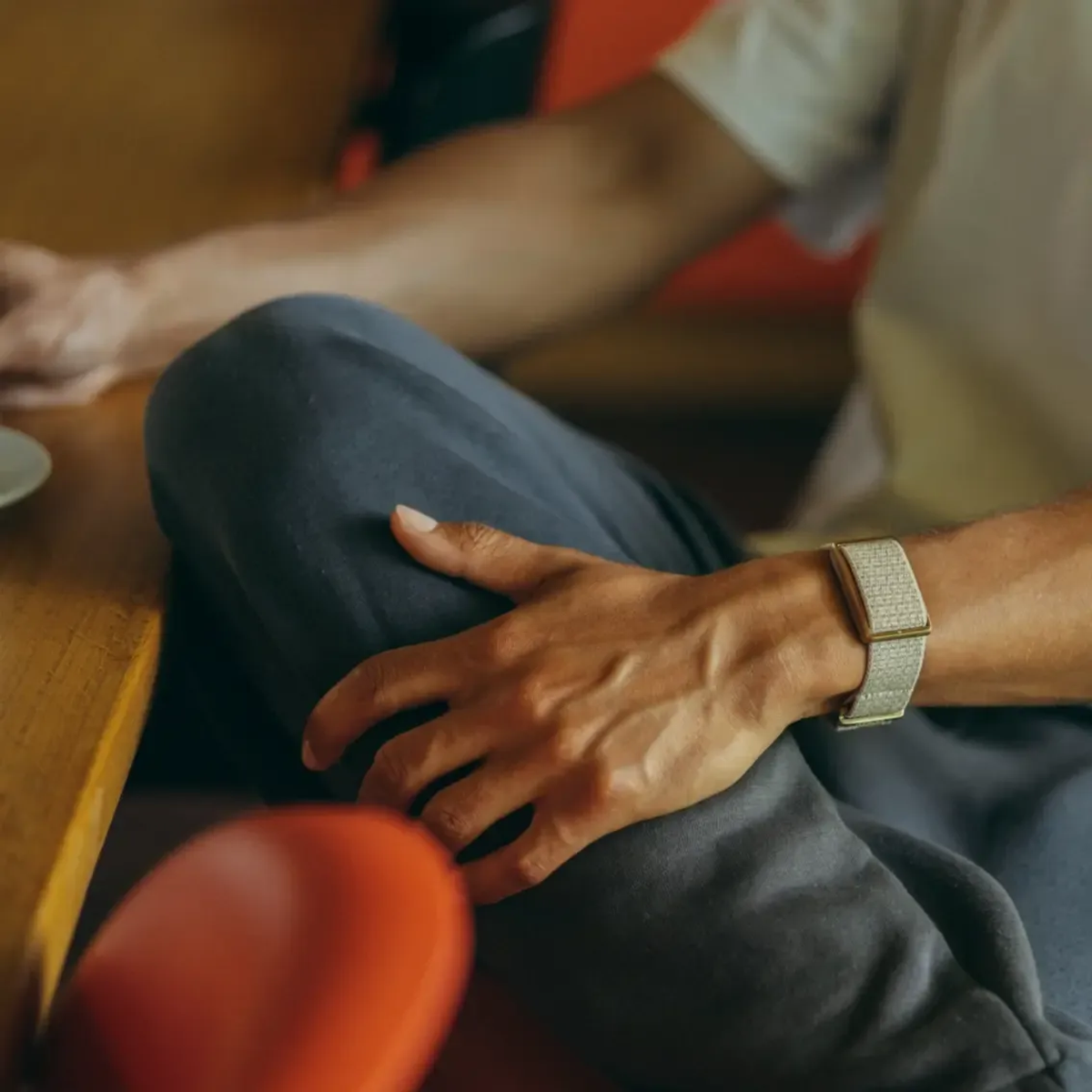 Primer plano de un hombre con brazalete plateado. Lleva camiseta blanca.