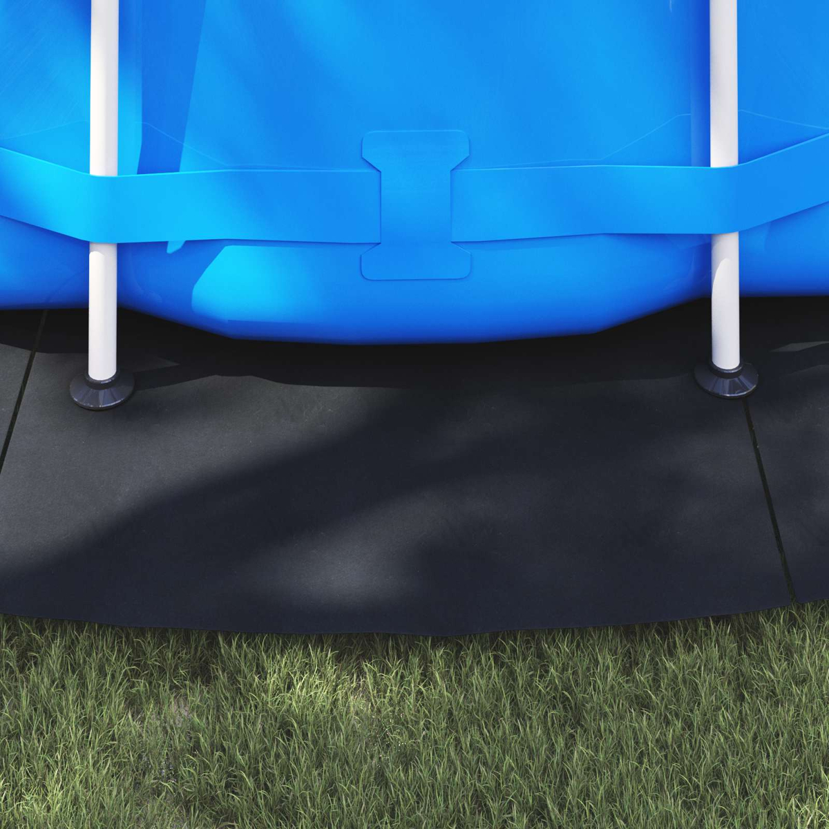 Ein Teil eines blauen Pools mit weißen Stützen auf schwarzem Untergrund neben Gras.