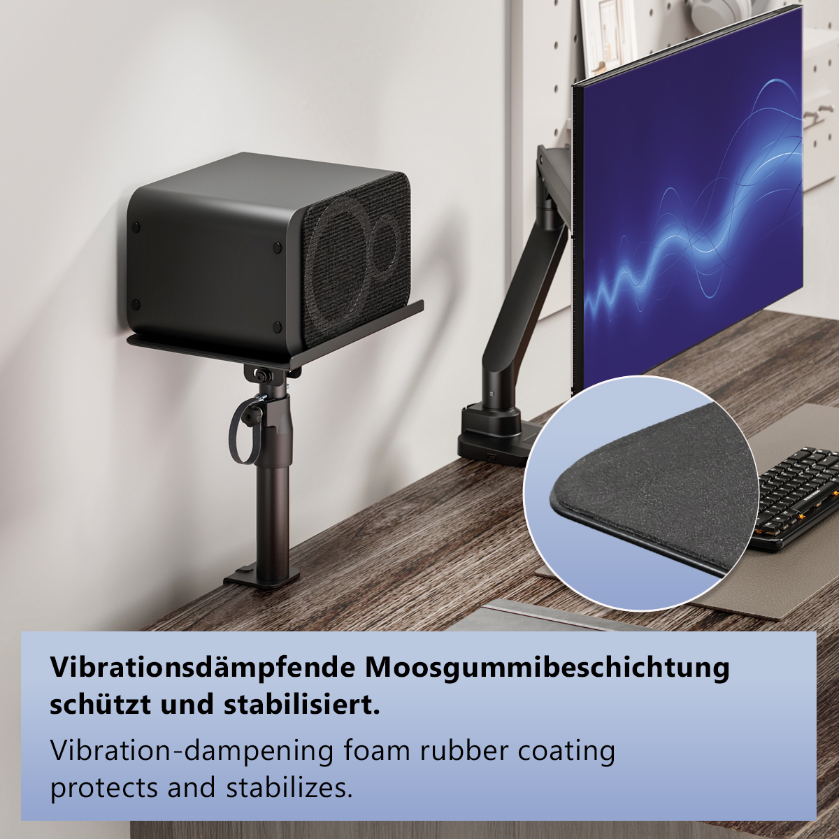 Ein schwarzer Lautsprecher auf einem Ständer, ein Monitor und eine Tastatur auf einem Schreibtisch.