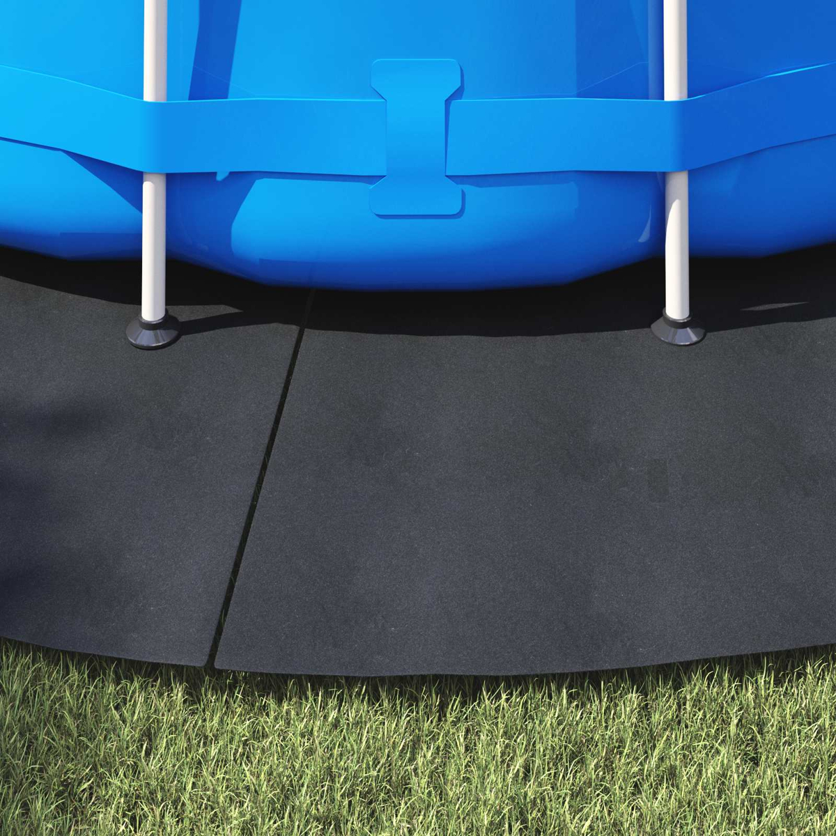 Ein blauer Pool steht auf schwarzem Boden neben Gras.