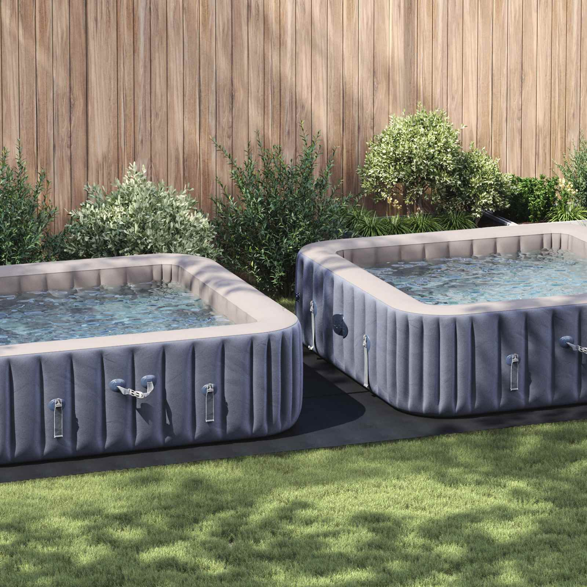 Zwei aufblasbare Whirlpools stehen im Garten vor einem Holzzaun.