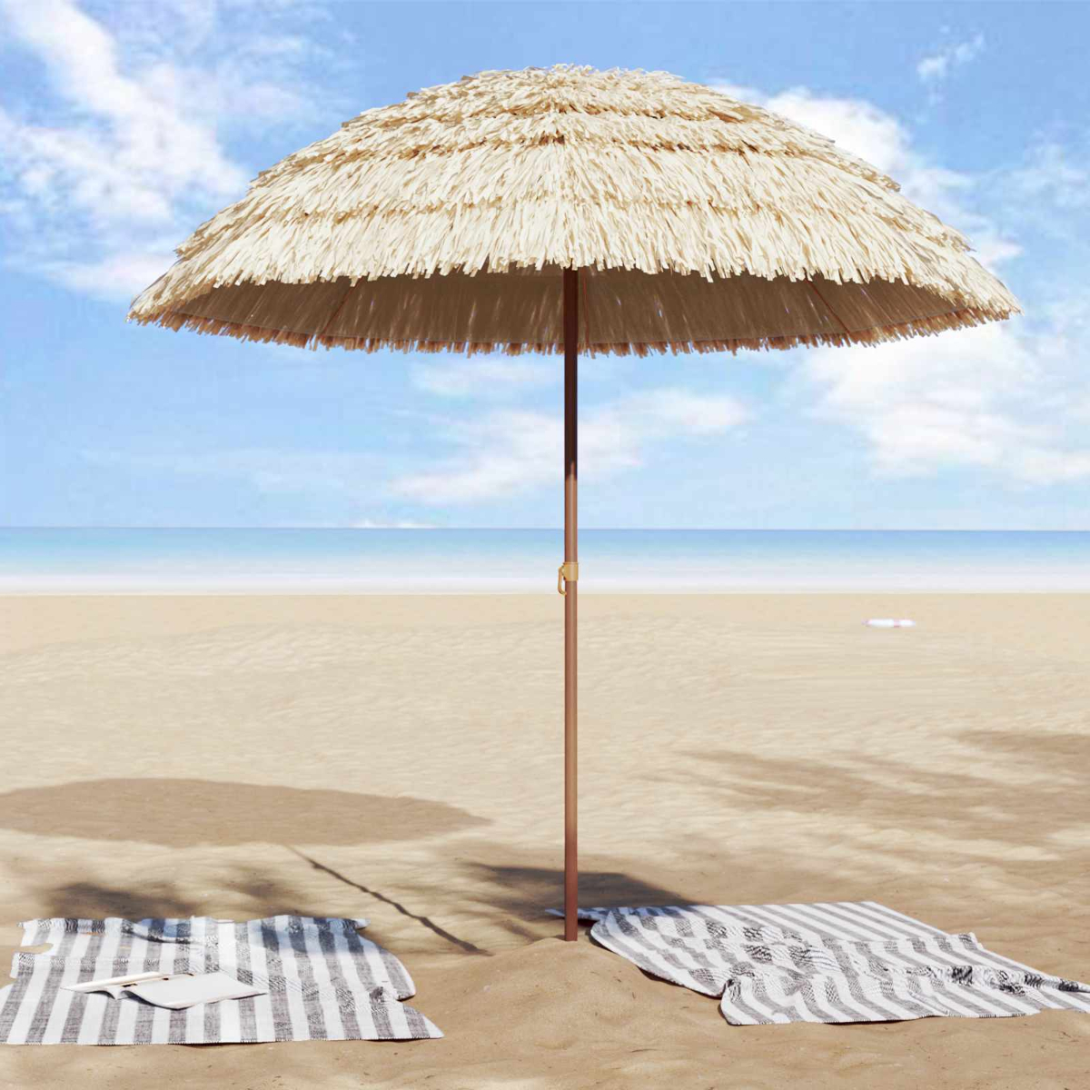 Un parasol de paja en la playa con dos toallas. El mar y el cielo al fondo.