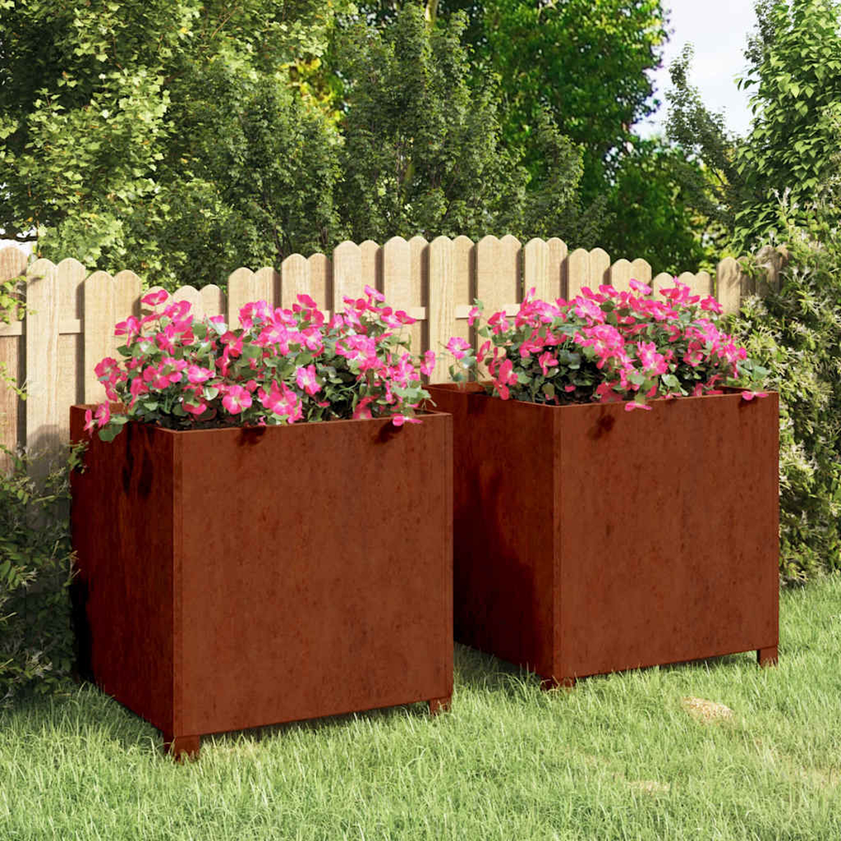 Zwei rostige Metallpflanzkübel mit rosa Blumen auf sattem Gras.