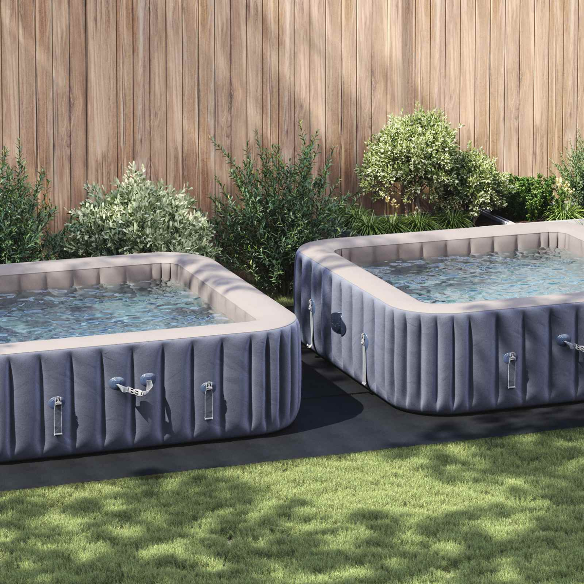 Zwei aufblasbare Whirlpools im Garten, gefüllt mit Wasser, vor einem Holzzaun.