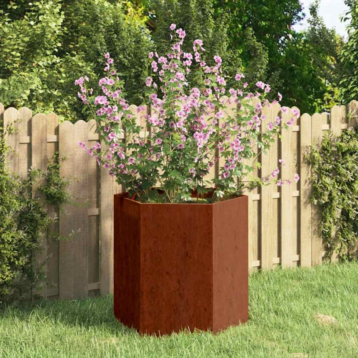 Ein sechseckiger Cortenstahl-Pflanzkasten mit rosa blühenden Pflanzen.
