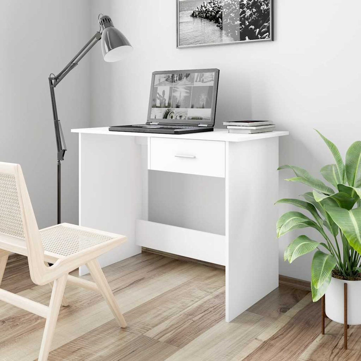 Ein weißer Schreibtisch mit Laptop, Büchern und Pflanze. Stuhl und Lampe in der Nähe.