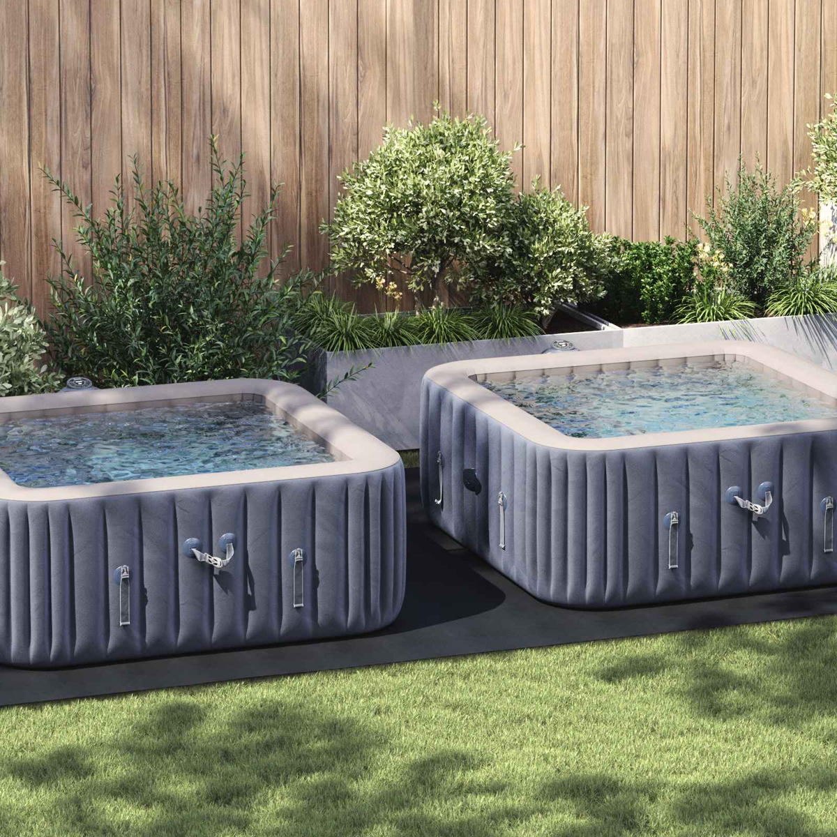 Zwei aufblasbare Whirlpools stehen im Garten auf Rasen vor Holzzaun.