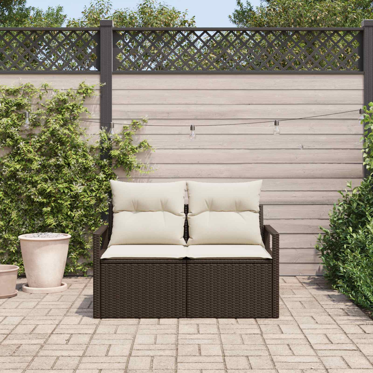 Eine dunkelbraune Outdoor-Liege mit cremefarbenen Kissen steht auf einer Terrasse.