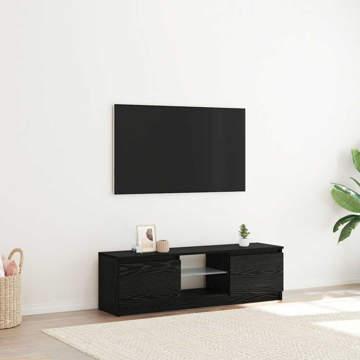Ein schwarzer TV-Schrank mit offenem Fach und Türen, daneben ein Korb.