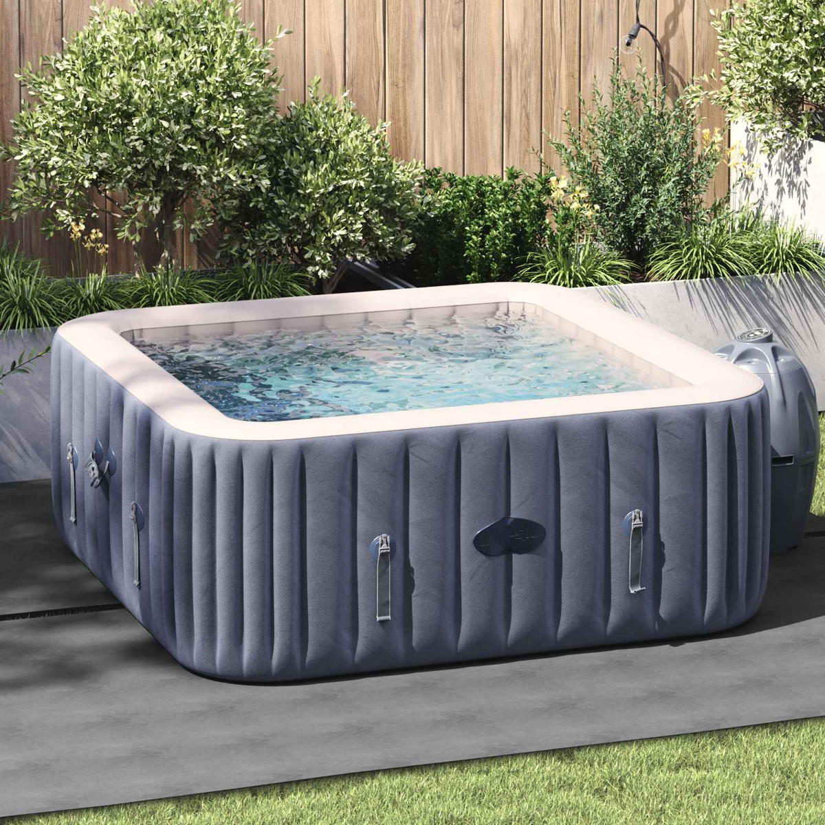 Aufblasbarer Whirlpool mit klarem Wasser, umgeben von Grün und Holzwand.