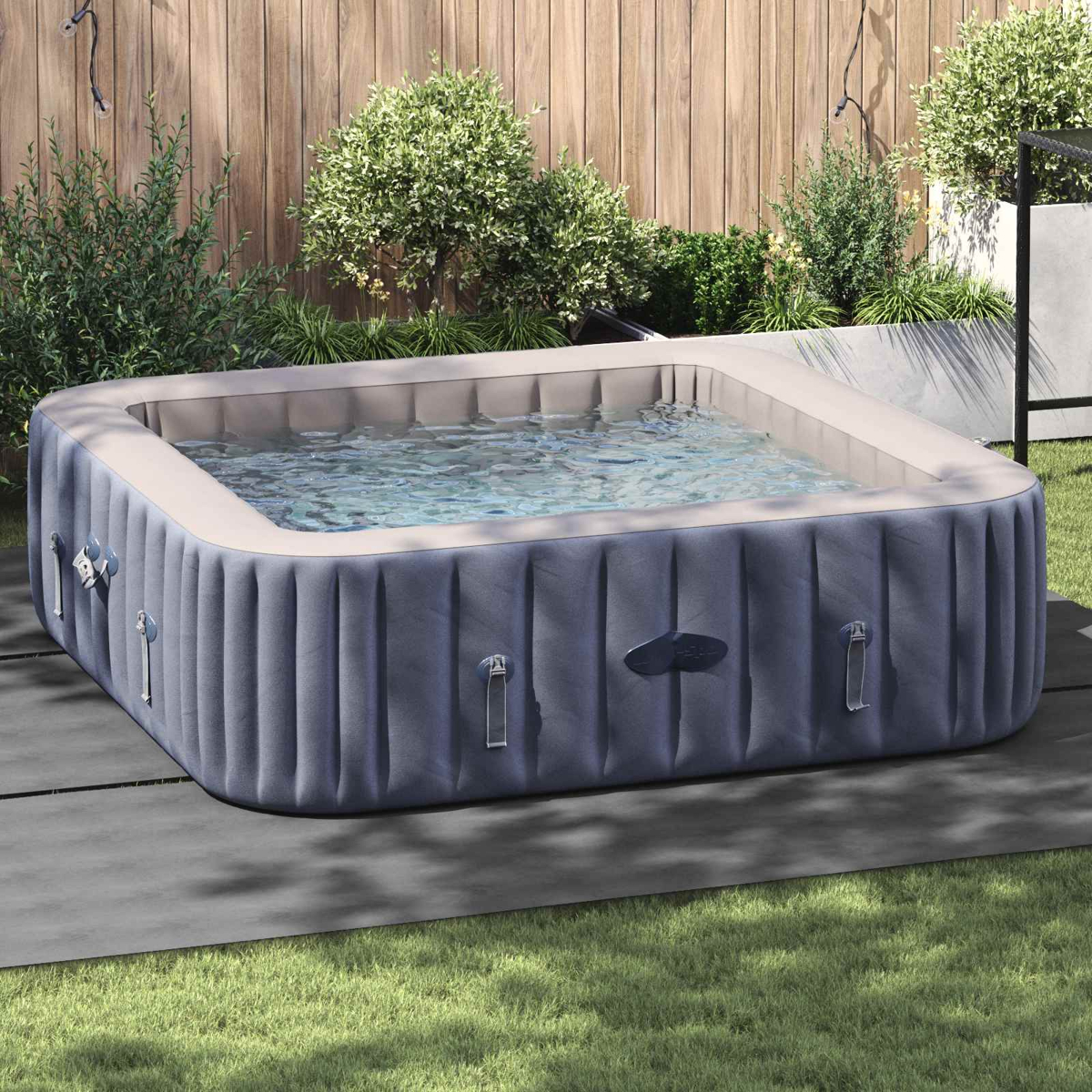 Aufblasbarer Whirlpool mit klarem Wasser, auf Terrassenplatten im Garten.
