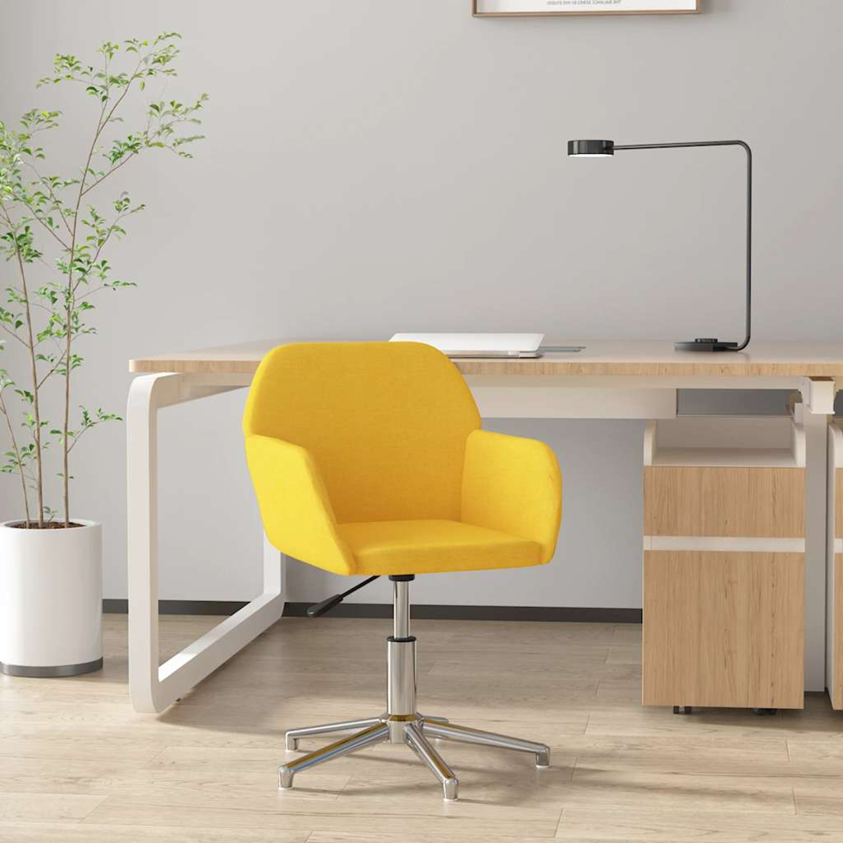 Ein gelber Bürostuhl steht vor einem Schreibtisch mit einem Laptop und einer Lampe.
