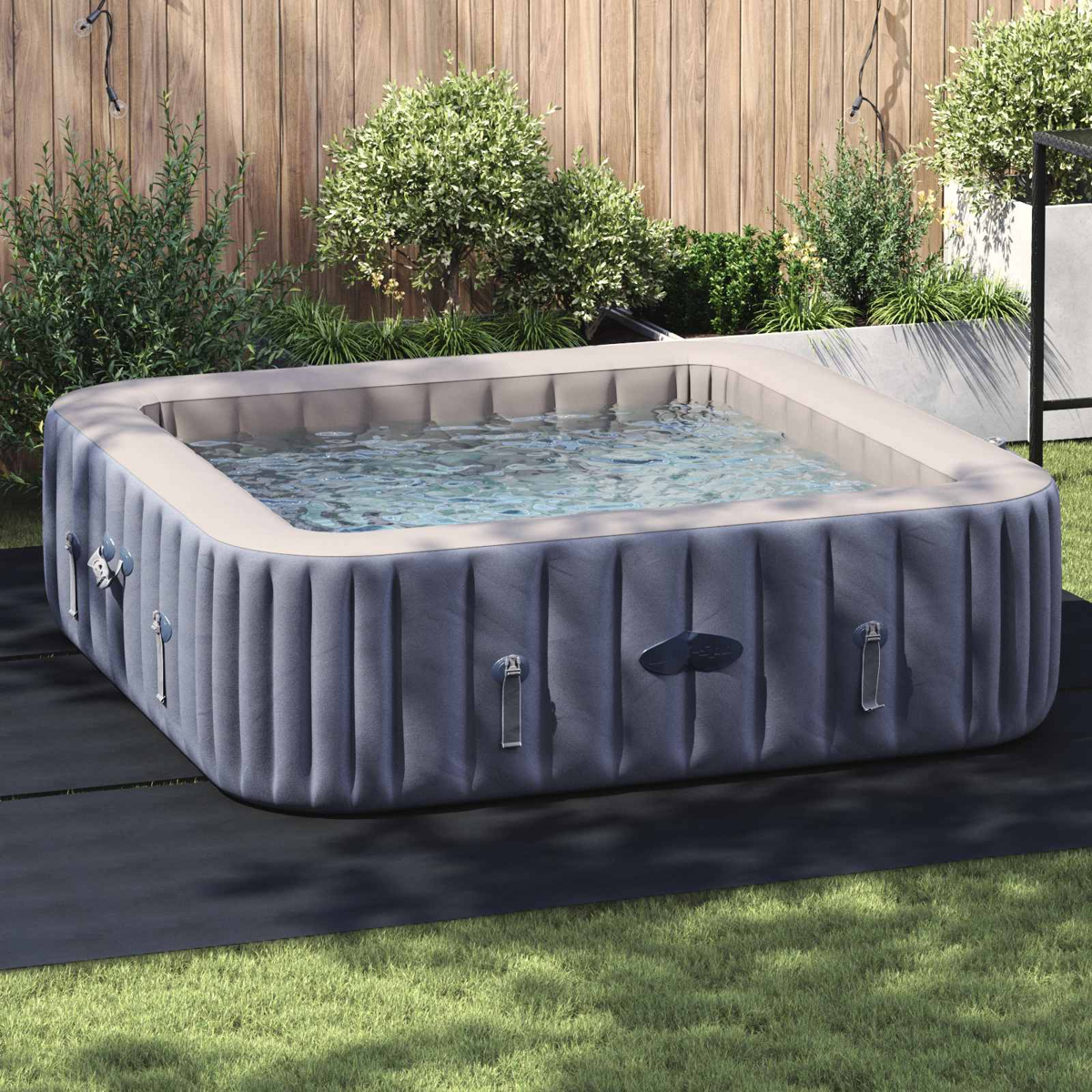 Aufblasbarer Whirlpool mit Wasser im Garten auf schwarzer Matte.