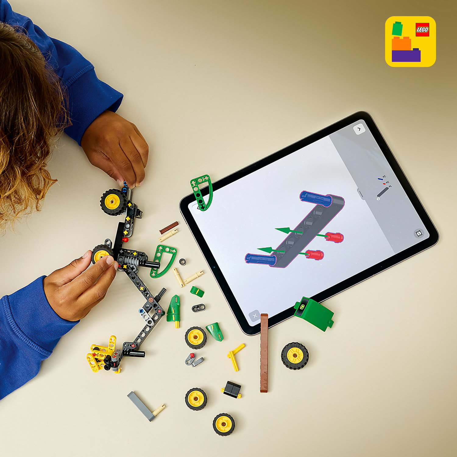 Dziecko buduje traktor z Lego, tablet pokazuje instrukcje.